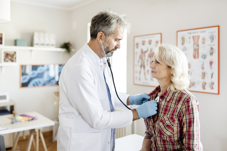 A doctor examines a patient's heart using a stethoscope. 