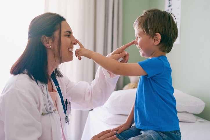 A provider and young boy playfully touch each other's noses.