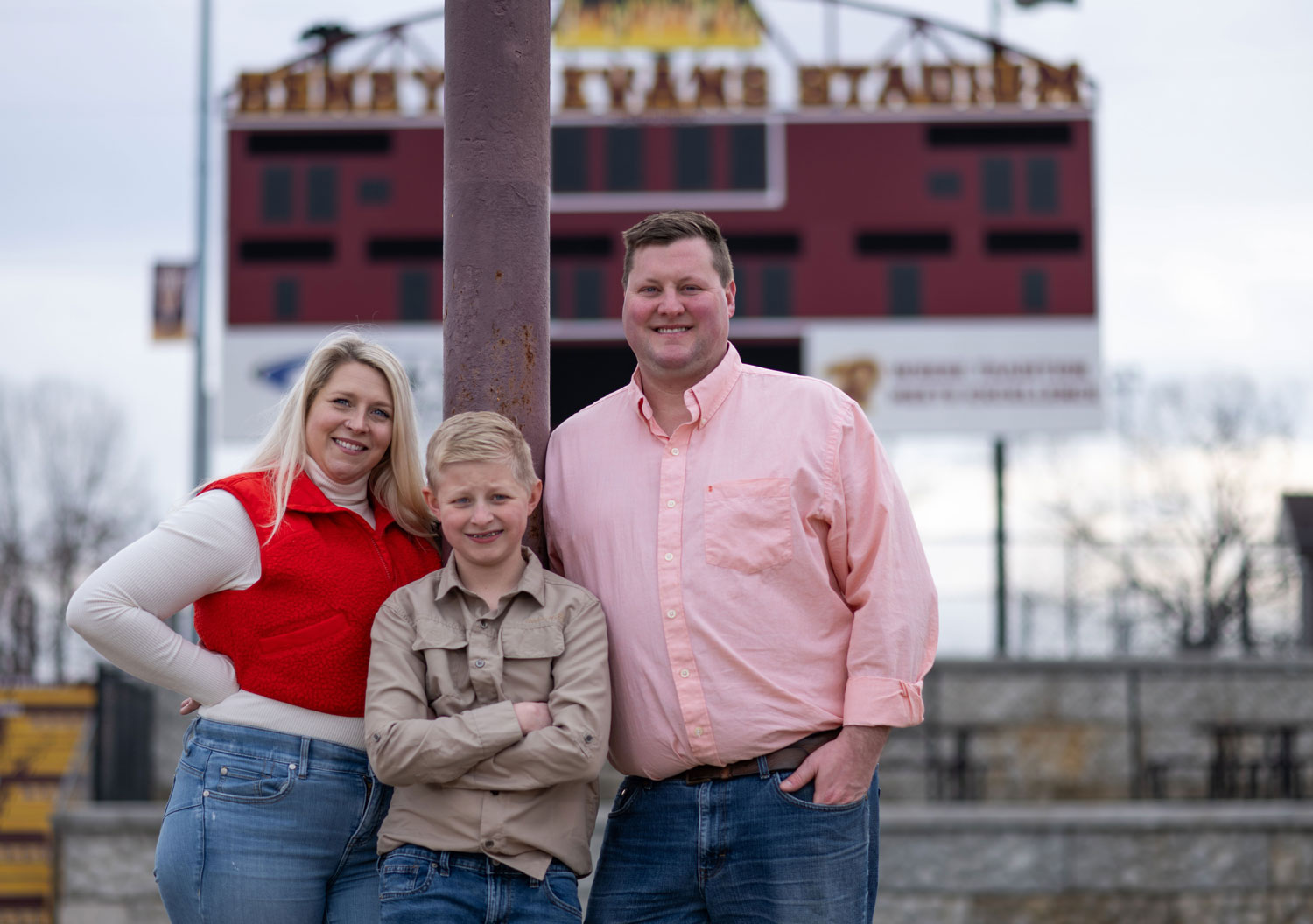 Brittany Dean, Wiliam Dean and Tyler Dean stand in front of the scoreboard at Russell's football stadium.