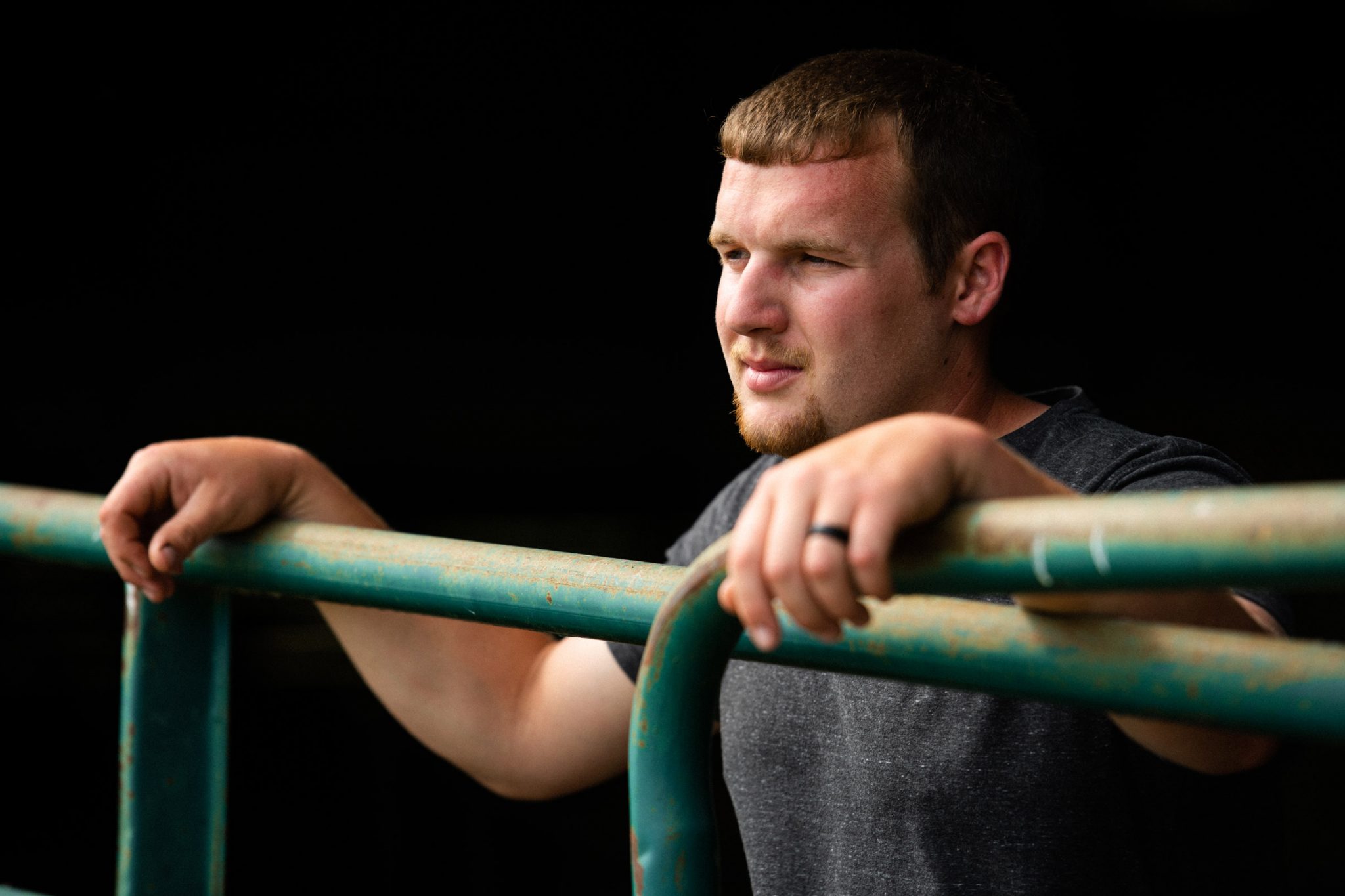Caleb watches his cows while leaning against the pen's railing.