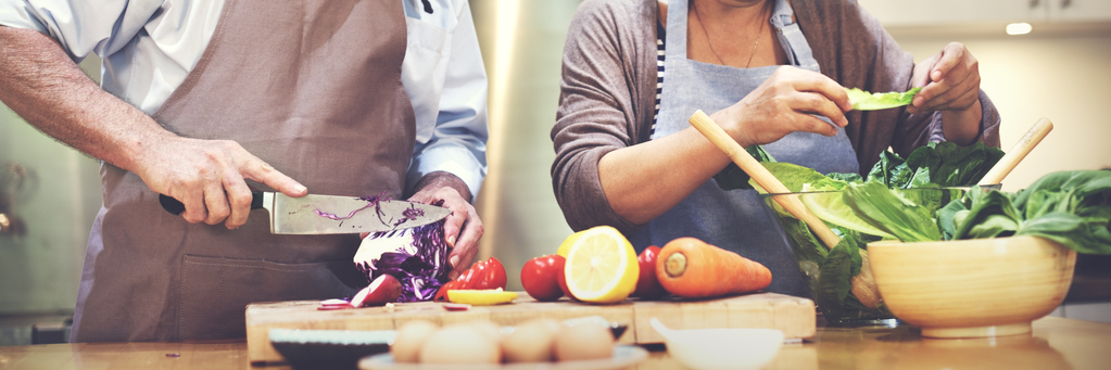 Couple cuts vegetables for a salad together.