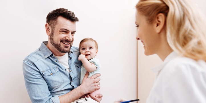 Dad holds his baby at the doctor's office.