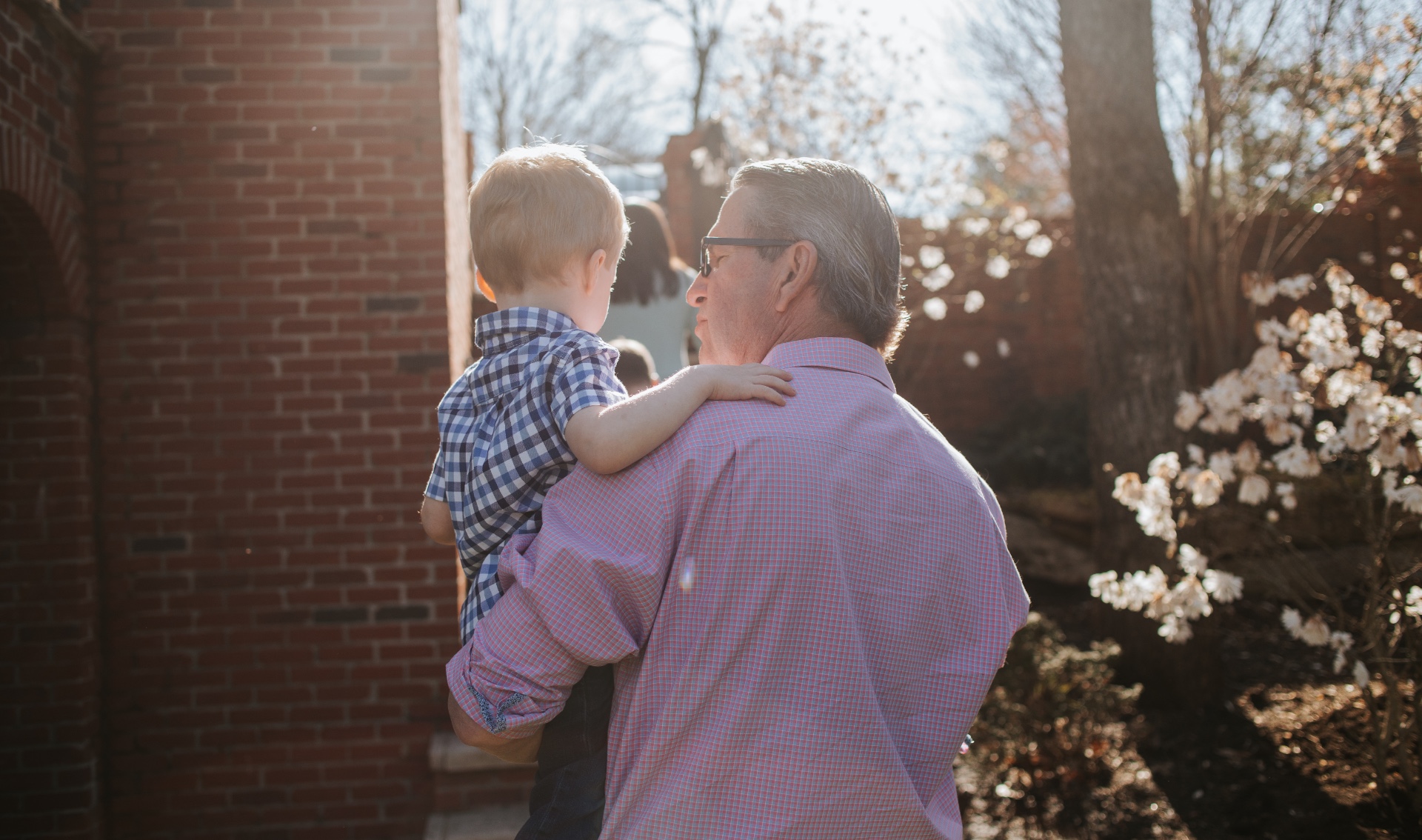 Using one arm, Dr. Johnson carries his grandson outside.