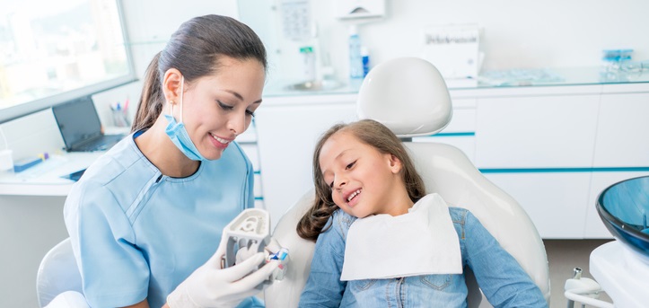 Girl at the dentist learning how to brush her teeth