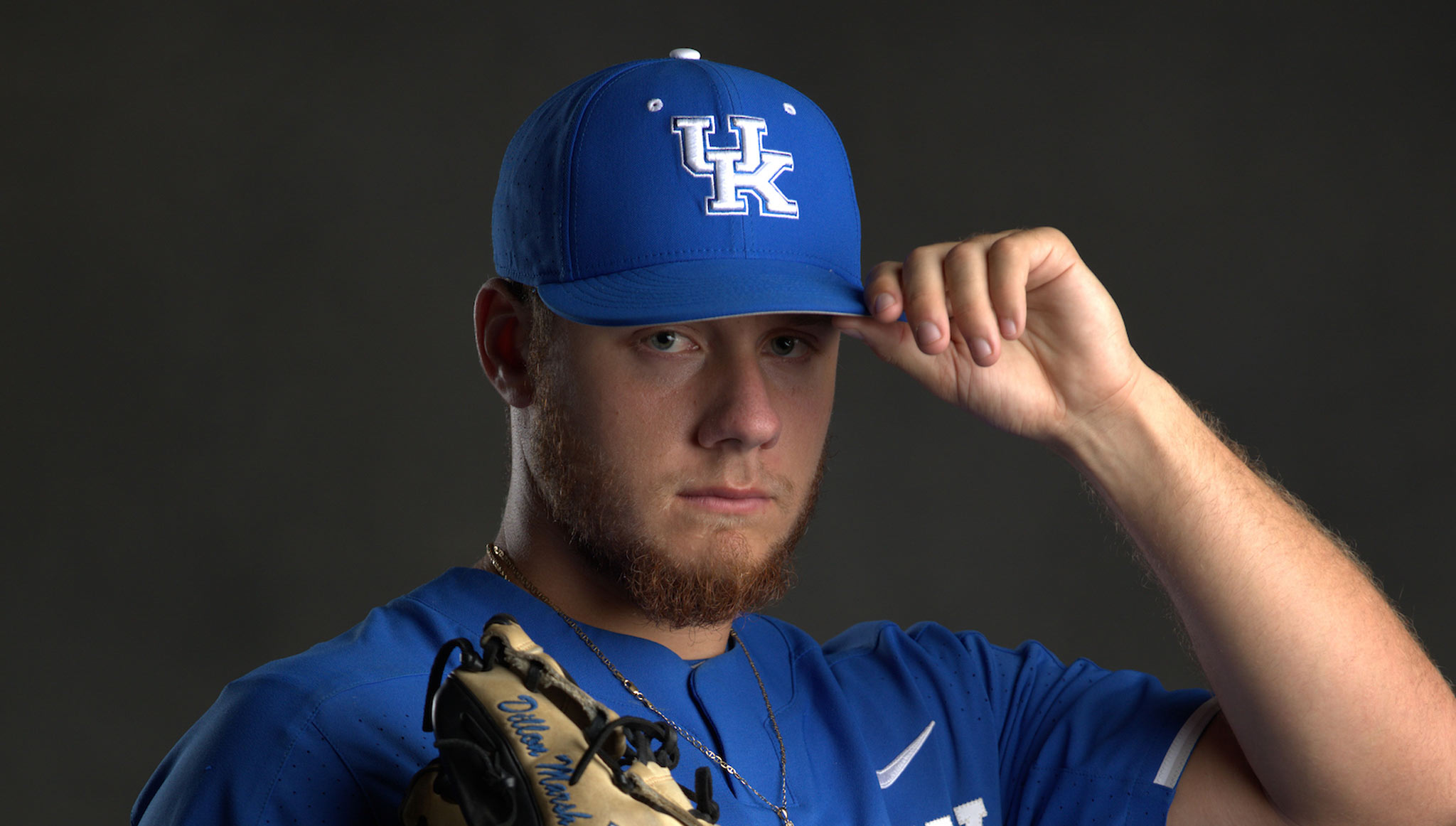 Dillon Marsh poses for a team portrait with his baseball glove and UK team baseball cap and jersey on.