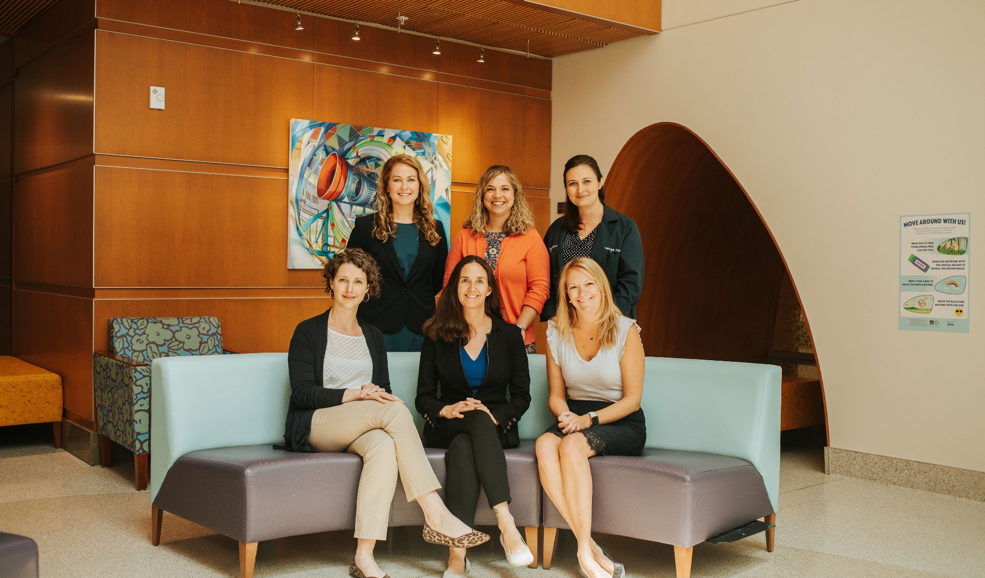 A group photo of the Pediatric Advanced Care team smiling as they pose together in their office.