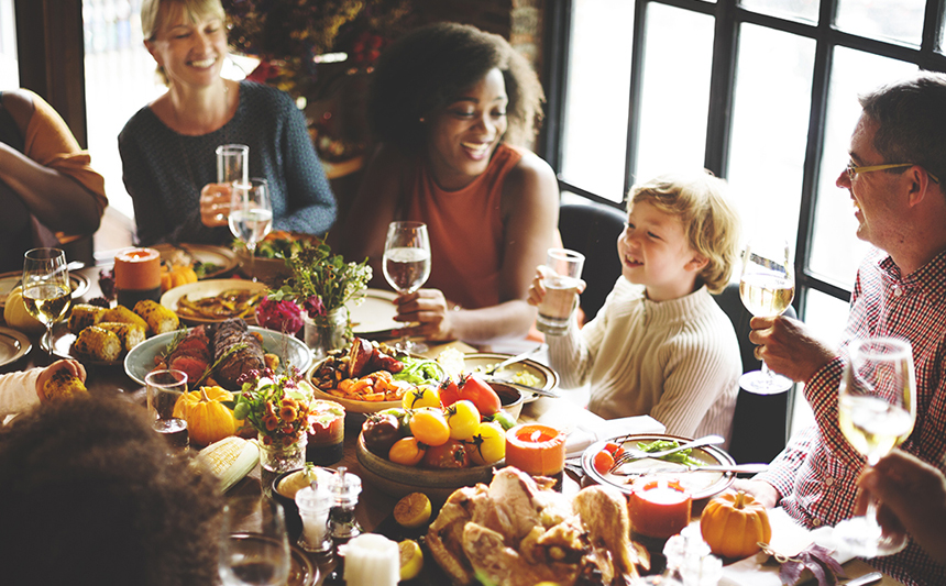 A group of people gathered around the dining table for Thanksgiving.