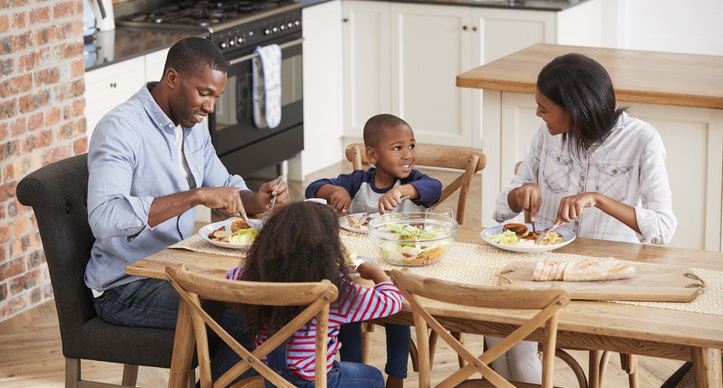 Family of four eats together at dinner table.