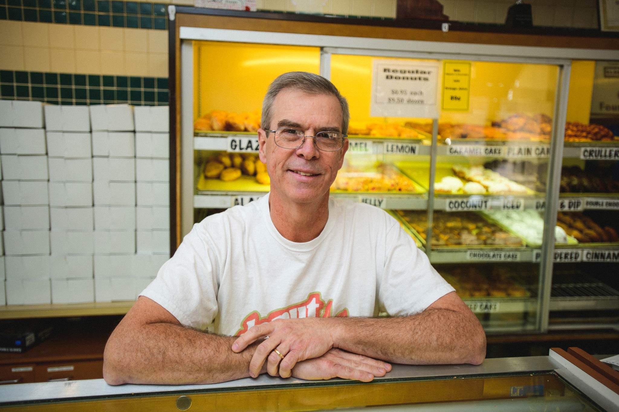 Fred Wohlstein leans against a counter at the doughnut shop and smiles.