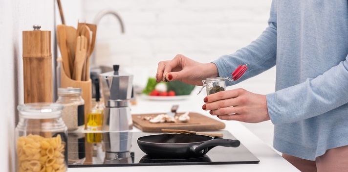 Woman spices food in pan