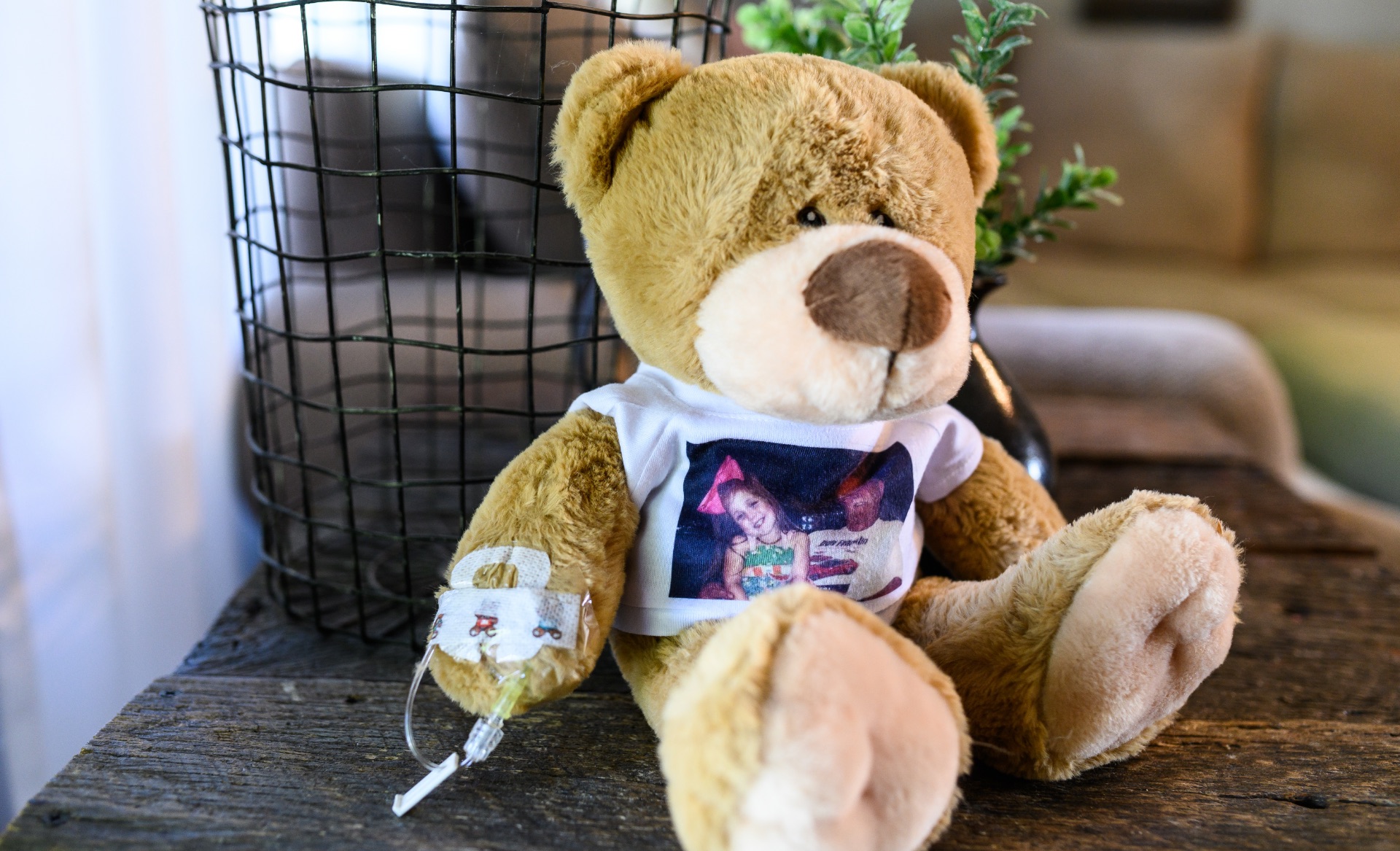 Henley’s teddy bear Donnie, a brown stuffed bear wearing a white shirt with a picture of Henley and her grandfather printed on it. Donnie has an IV connected to one of his arms.