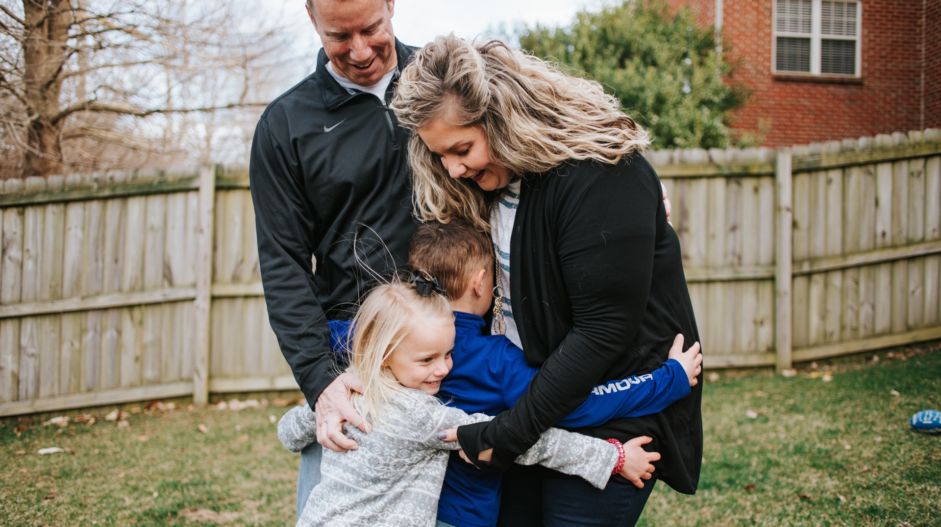 The Longeway family stand embraced together in an outside setting. Amongst them is Amy Longeway, a blonde white woman in a black cardigan, her husband, in a black sweatshirt, Henry in a blue sweatshirt and his younger sister in a grey sweatshirt.