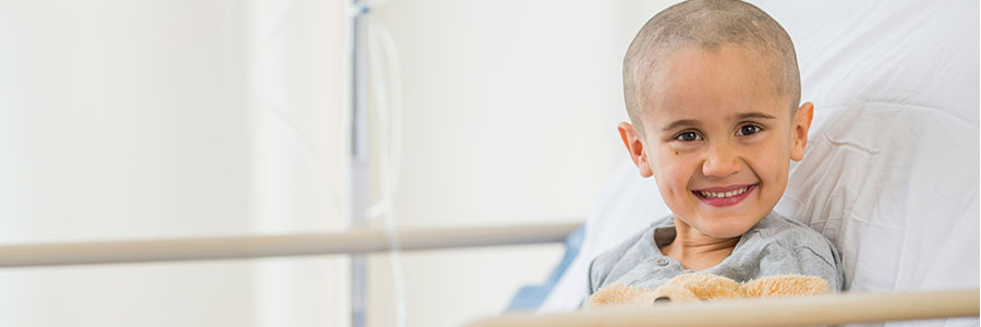 Boy with teddy bear in hospital bed