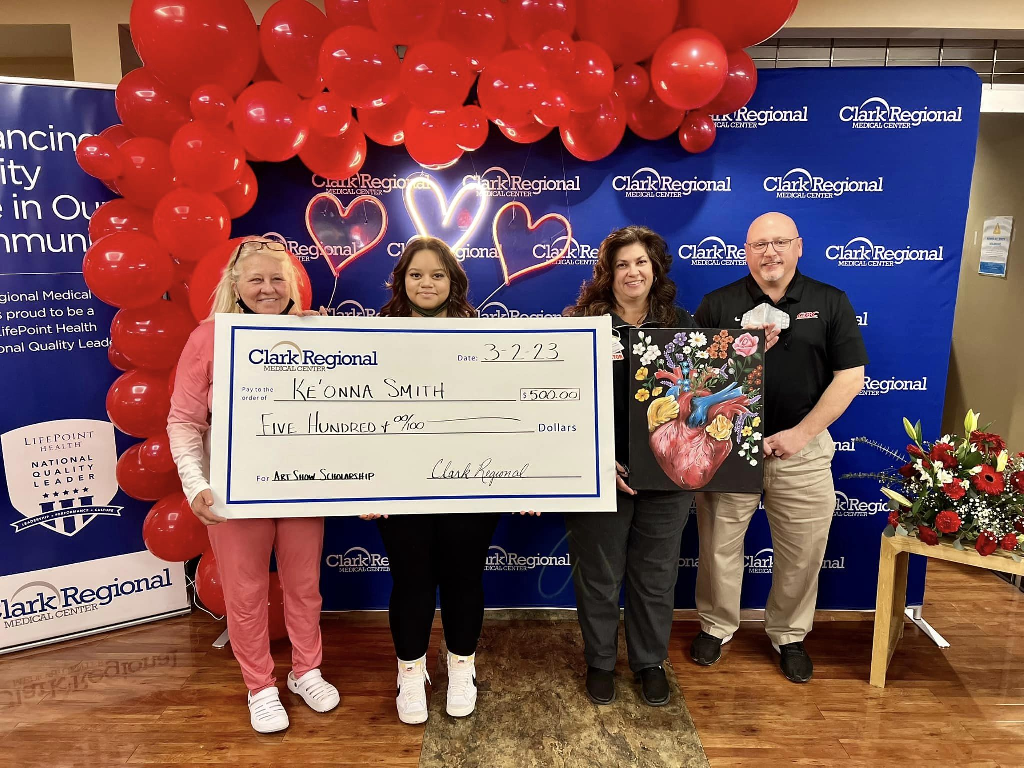 Ke'Onna Smith, a student, holds an oversized scholarship check for $500 awarded by Clark Regional Medical Center's heart program.