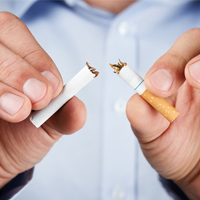 A man breaking a cigarette in half.