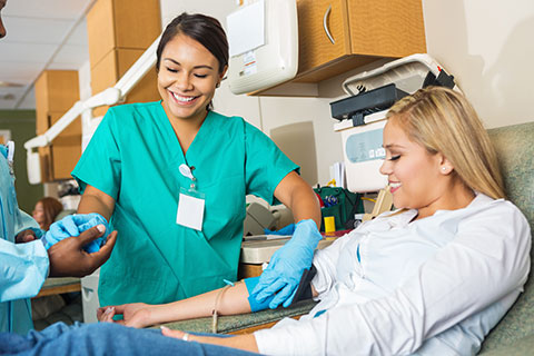 Nurse assisting coworker as she helps patient during a procedure.