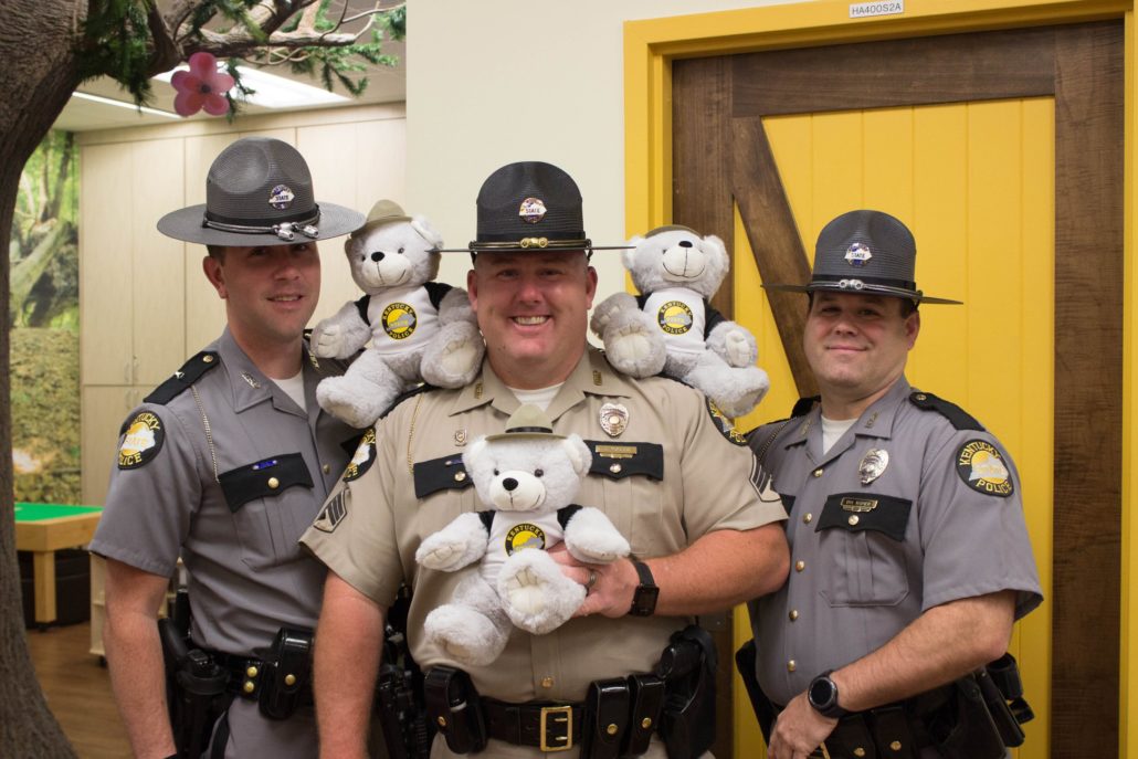 Three Kentucky State Troopers pose with teddy bears.