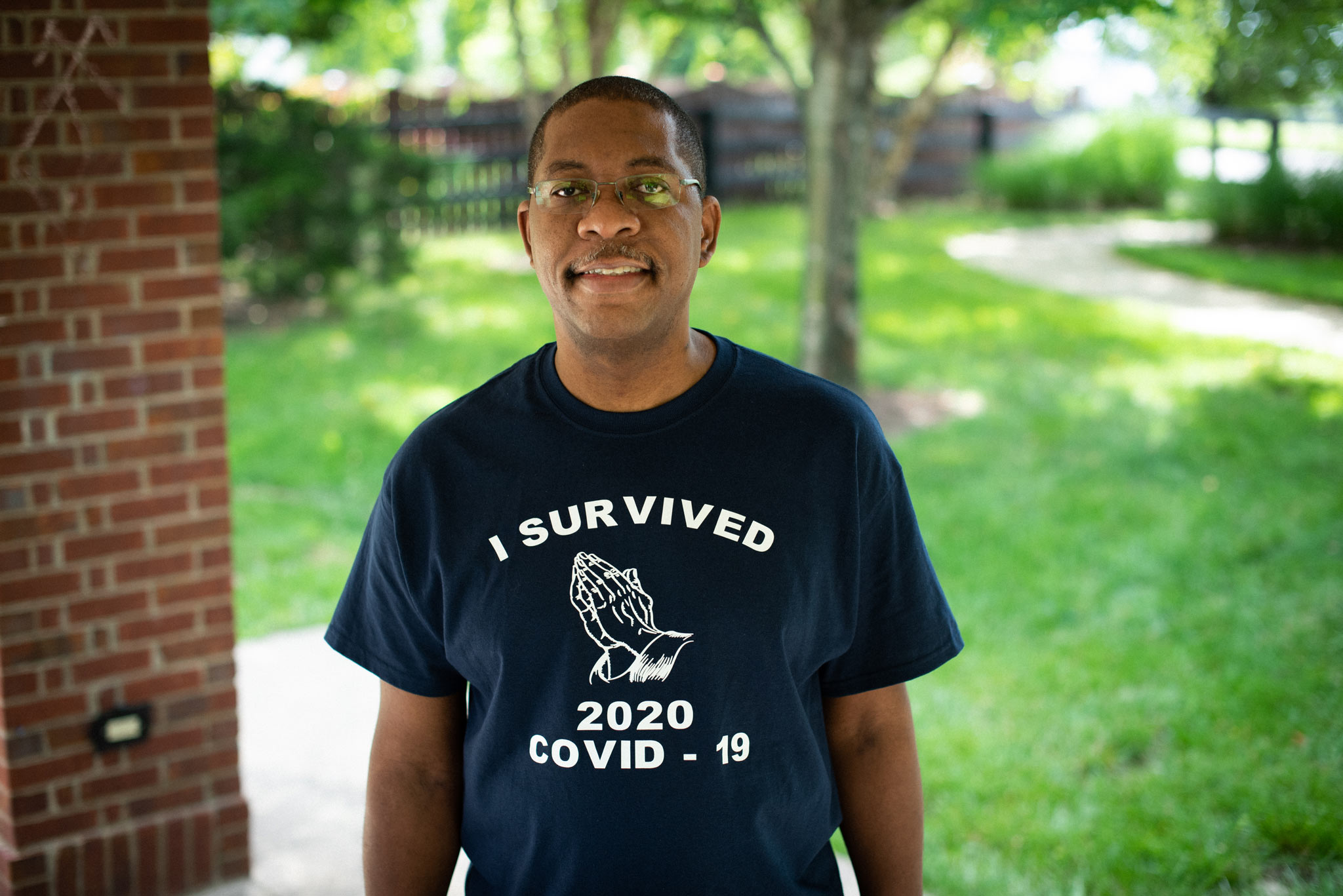 Portrait of Jerome outside smiling while wearing a shirt that says \
