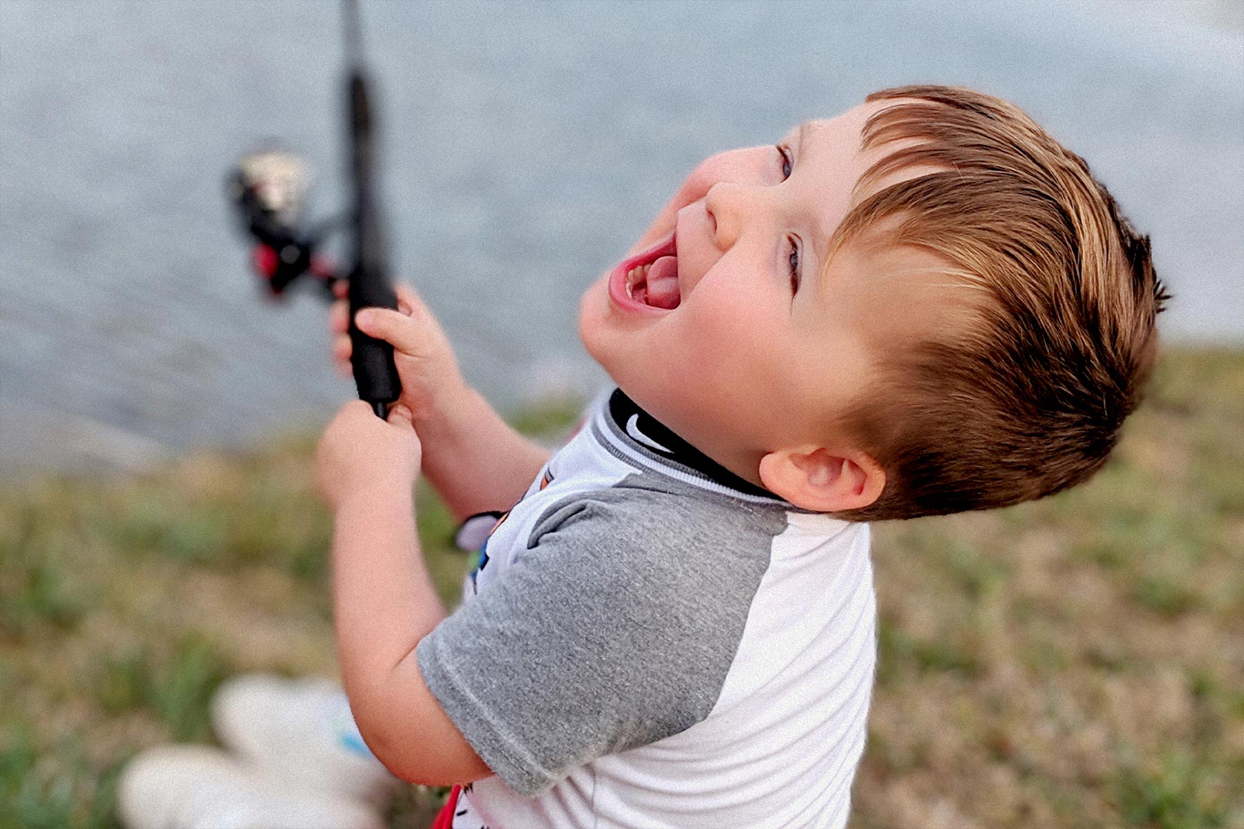 Kase laughs gleefully while holding a fishing pole.