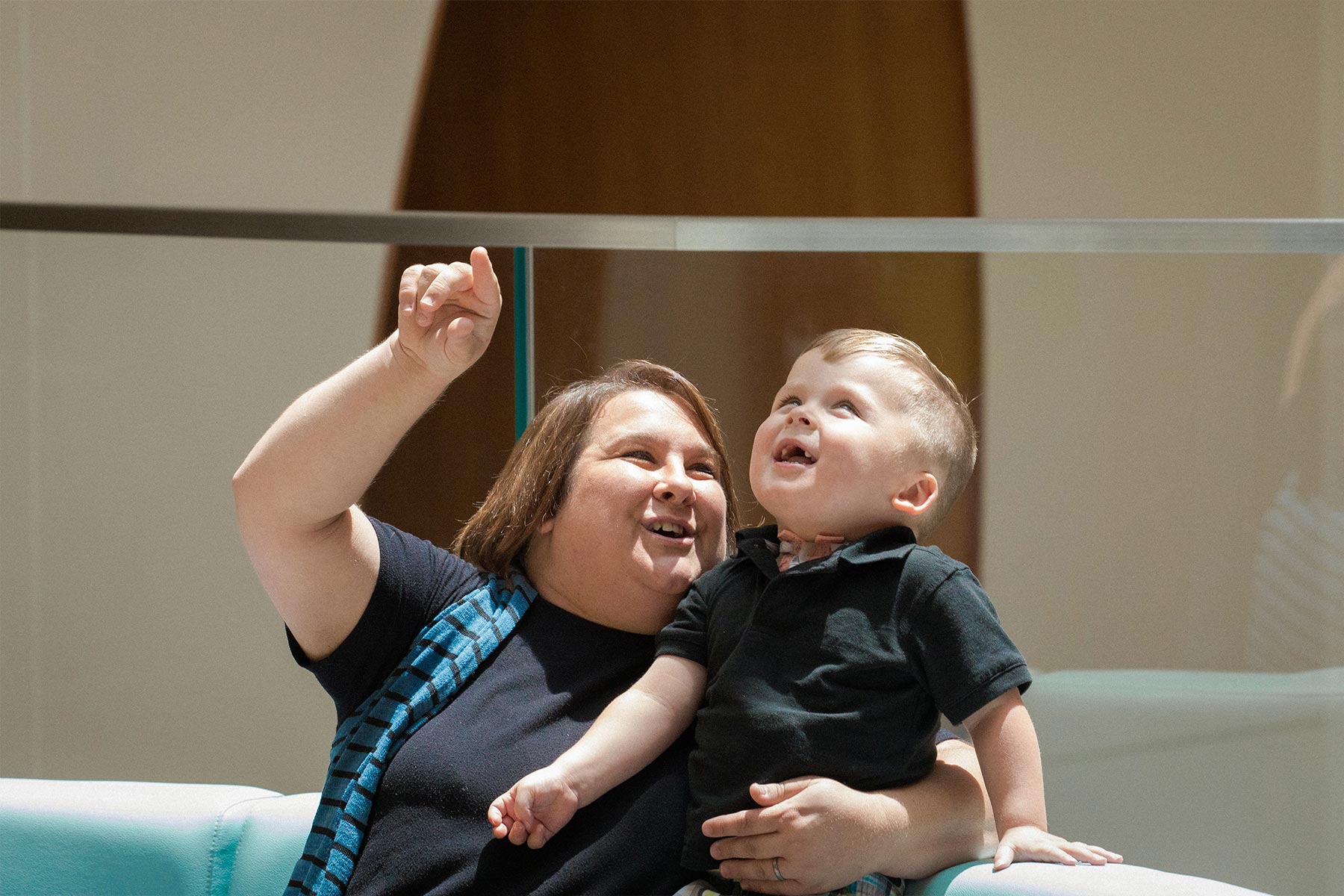 Hanna points up to show Kase something while holding him. Kase smiles and looks up at what she is showing him.