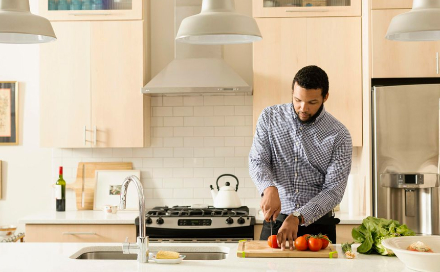 A man chops tomatoes in his kitchen.