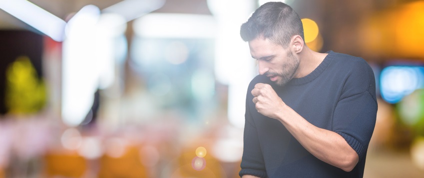 Middle-aged man coughs into his hand.