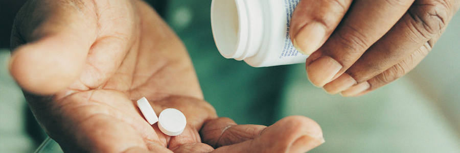 A man pours tablets into the palm of his hand.