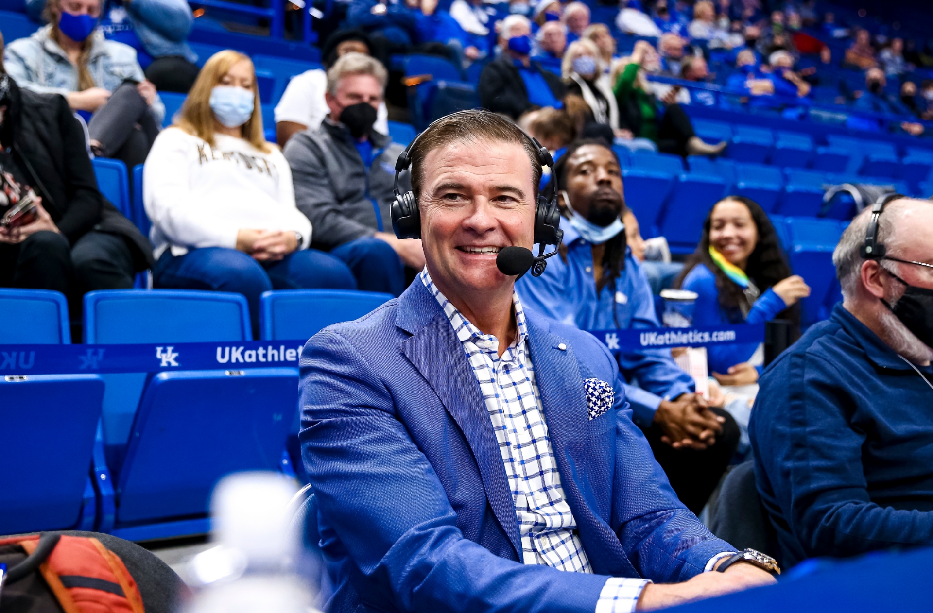 A photo of Coach Mitchell smiling as he looks off camera while sitting courtside at a UK game.