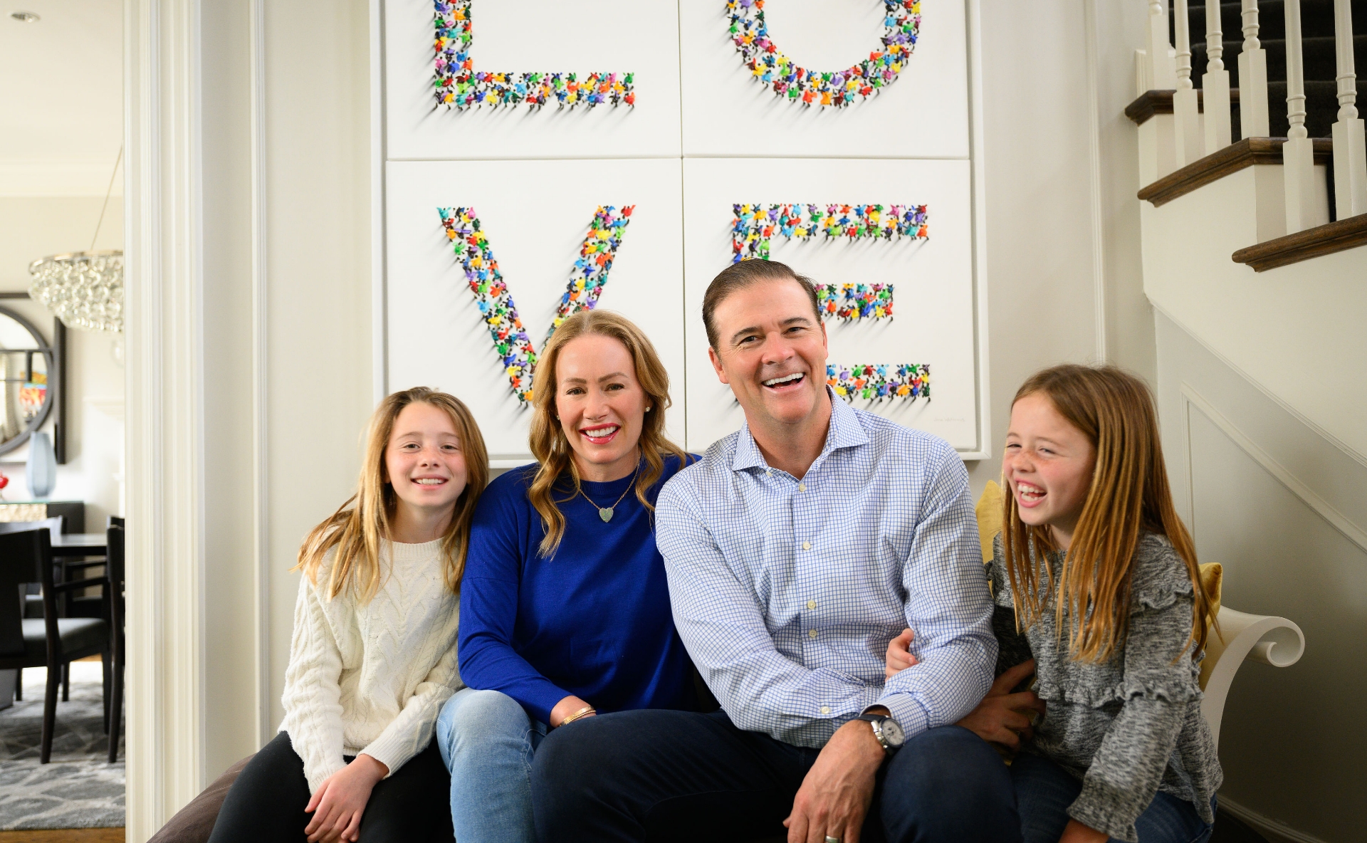 A candid photo of the Mitchell family laughing as they sit on the couch together.