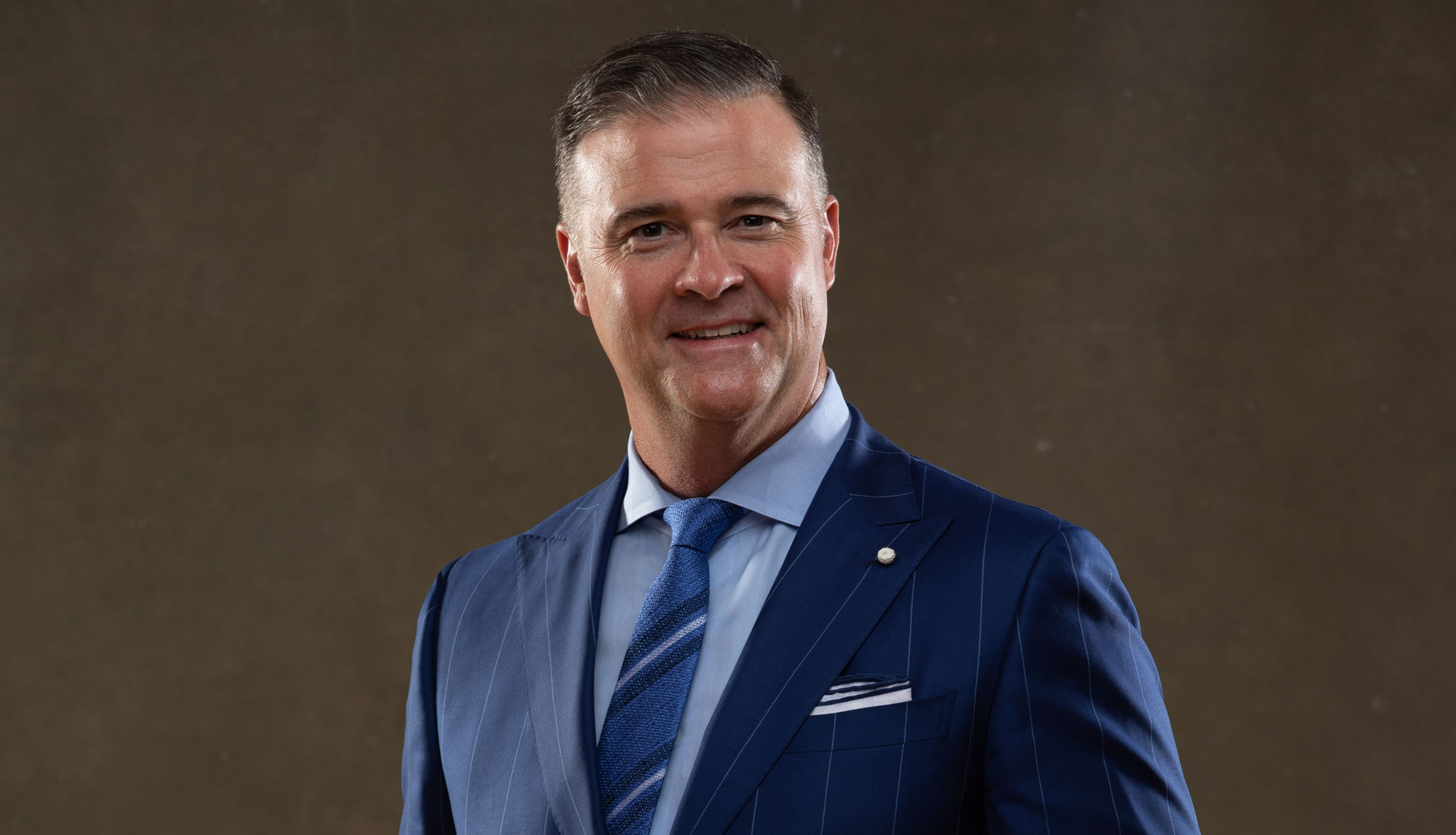 A formal portrait of Coach Mitchell in a blue suit.