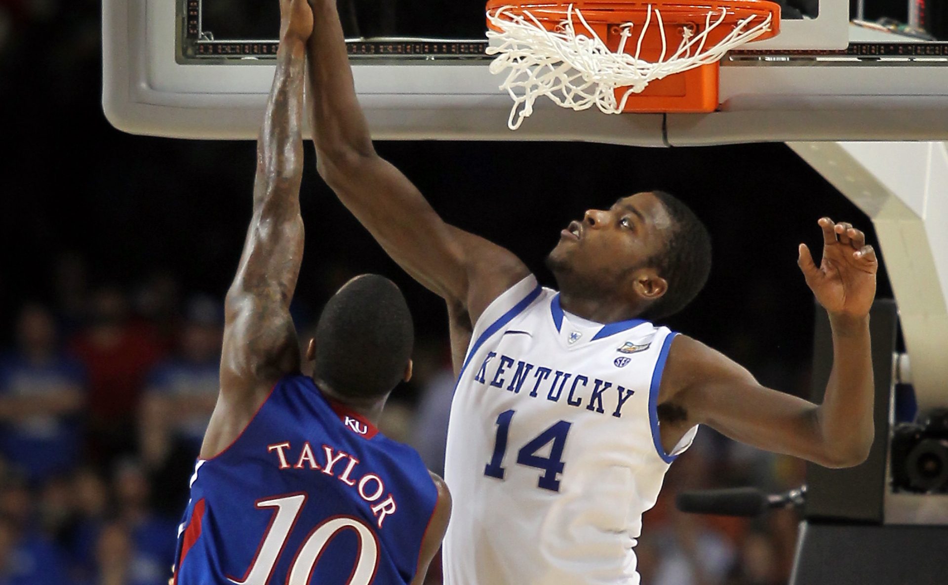 An action shot of Michael in mid-air blocking a Kansas basketball player from scoring.