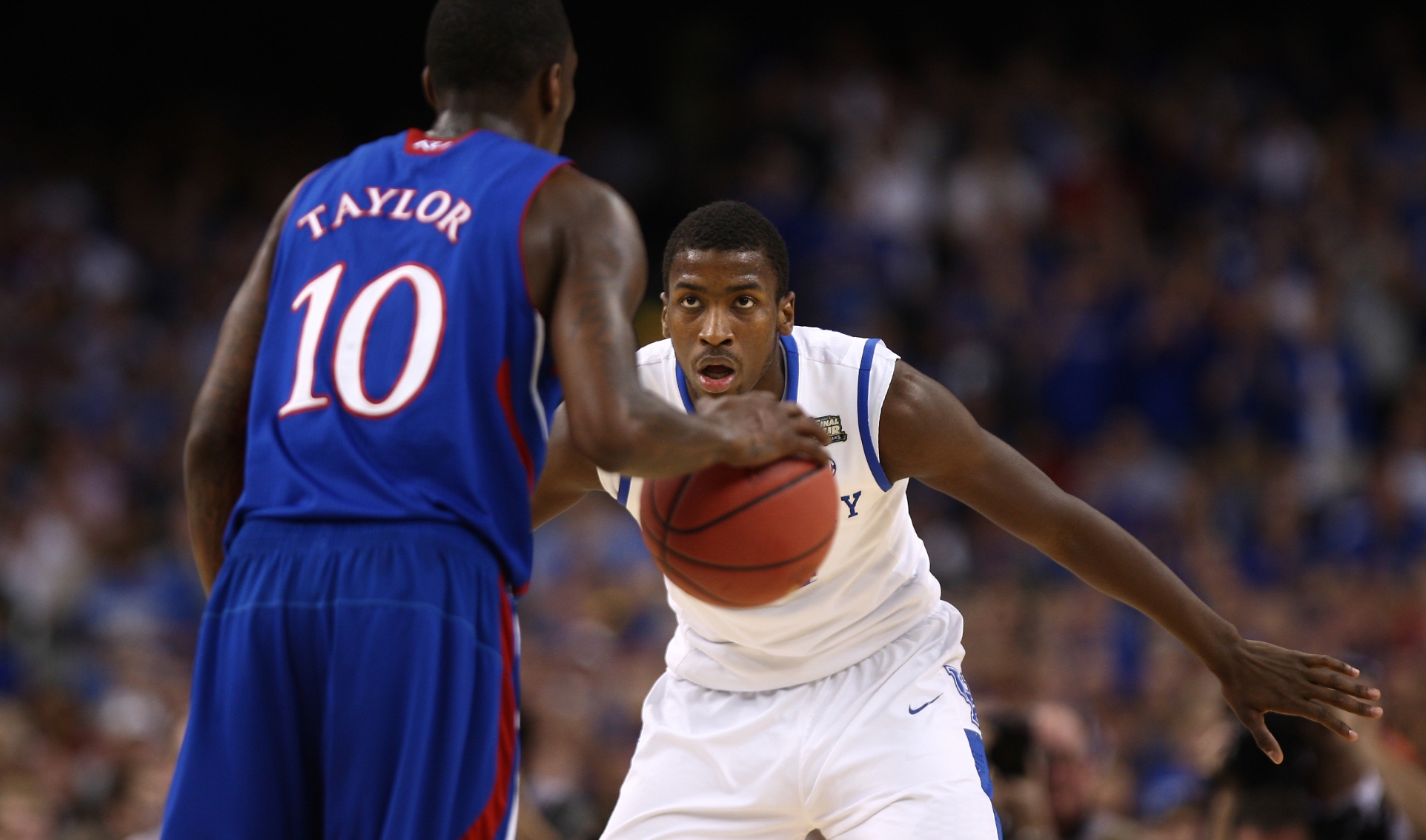 An action shot of Michael playing defense while a Kansas basketball player dribbles the ball.