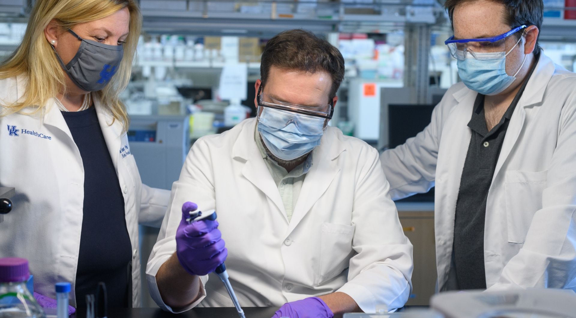 A photo of Dr. Jill Kolesar (left) and a colleague (right) looking on as a third doctor (center) uses a device.