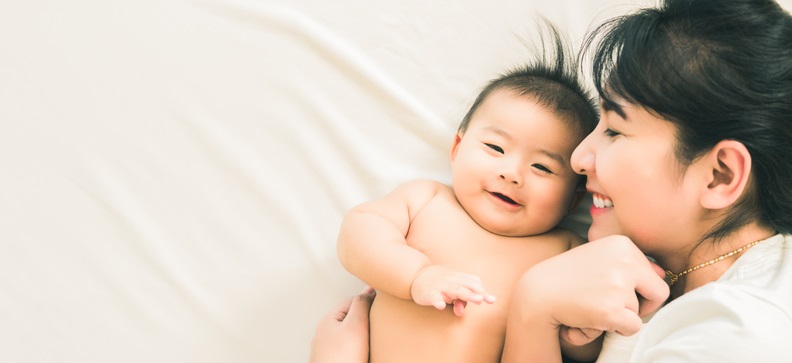 Mom lies on a bed with her baby.