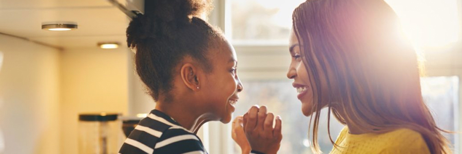 A mother and daughter smile and laugh together.