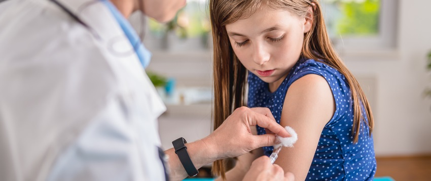 Nurse administers shot to young girl.