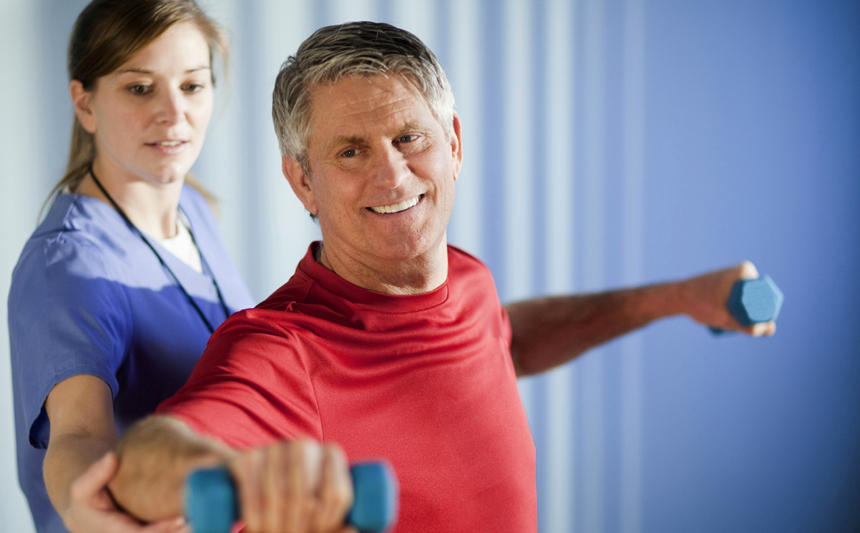 A physical therapist works with a patient using hand weights.