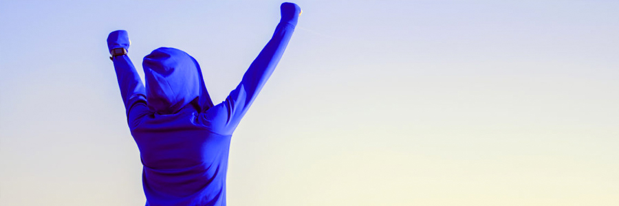 A runner in a hooded sweatshirt celebrates achieving a goal.