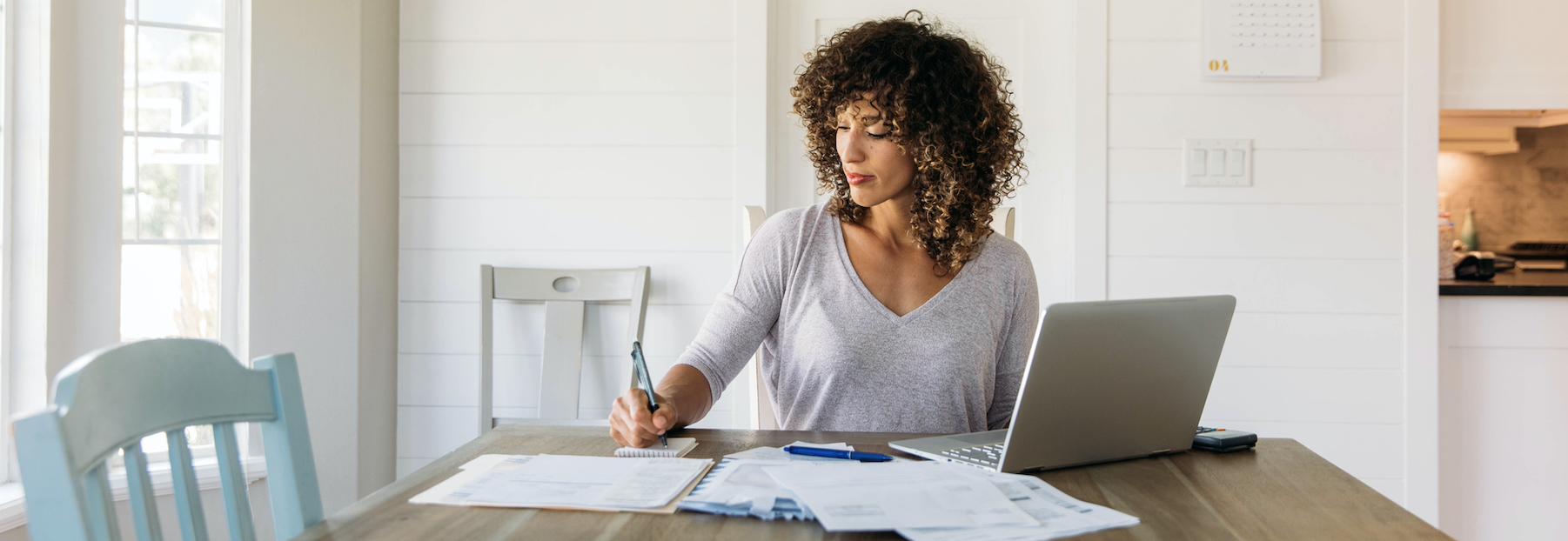 Woman with papers spread out in front of her, working from home. 