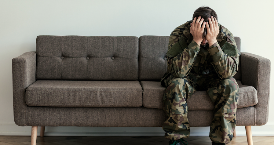 Solder with head down sitting on a couch.