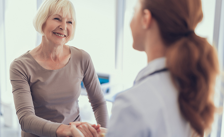 smiling woman shaking hands with female doctor