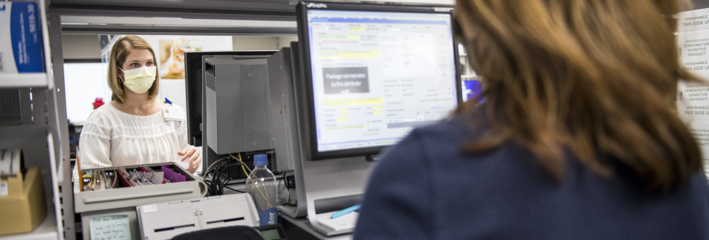 A pharmacy technician works at a computer filling prescription orders