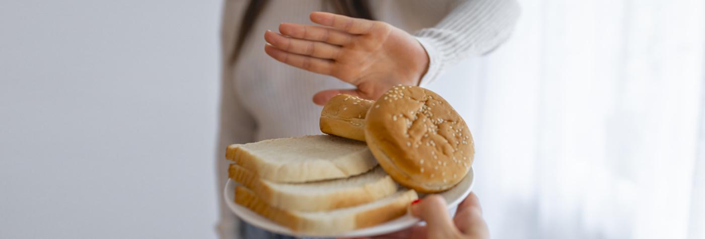 Woman holding up hand to say no to plate of baked goods.