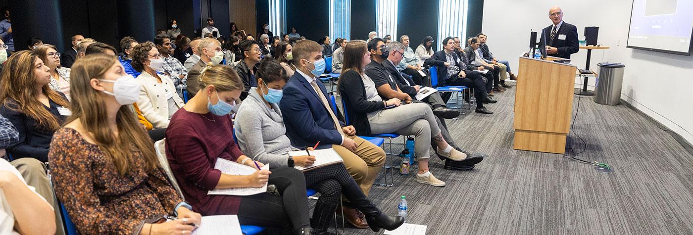 A group of symposium attendees listen to a presentation.