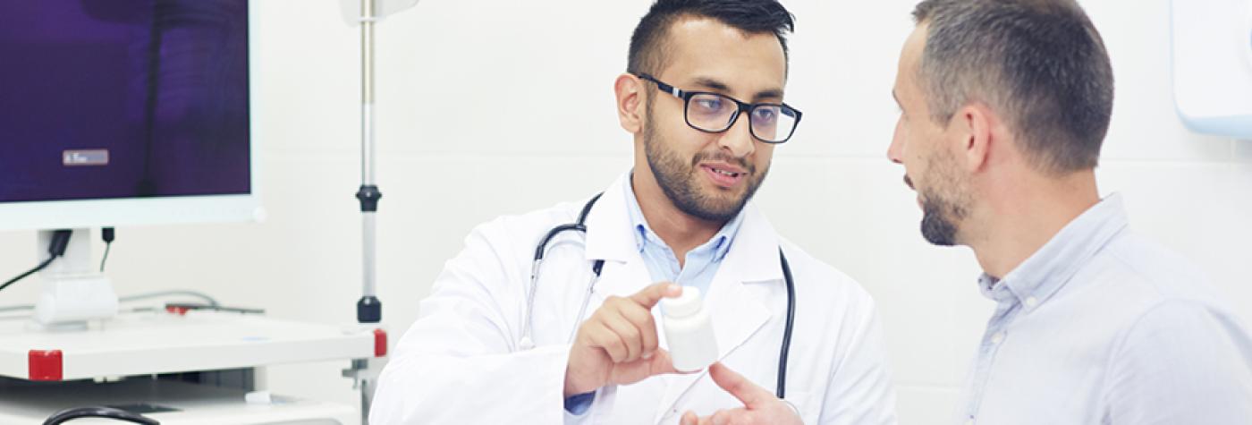 A doctor in a white coat and stethoscope having a conversation with a male patient