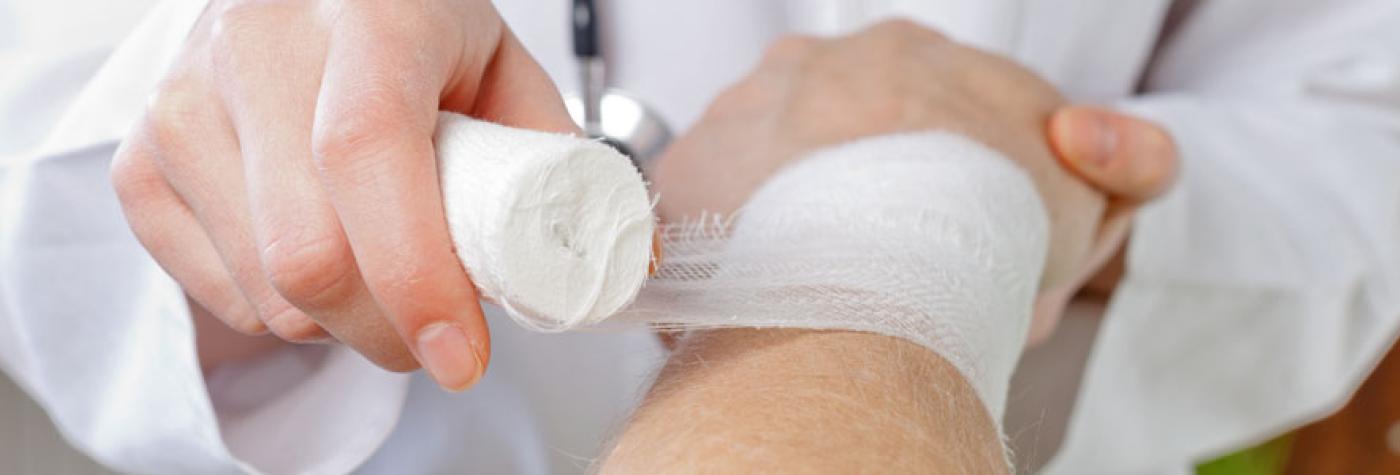 A doctor wraps a patient's wrist with gauze.