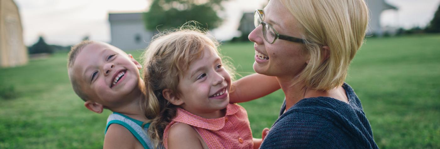 A mother plays outdoors with her children.