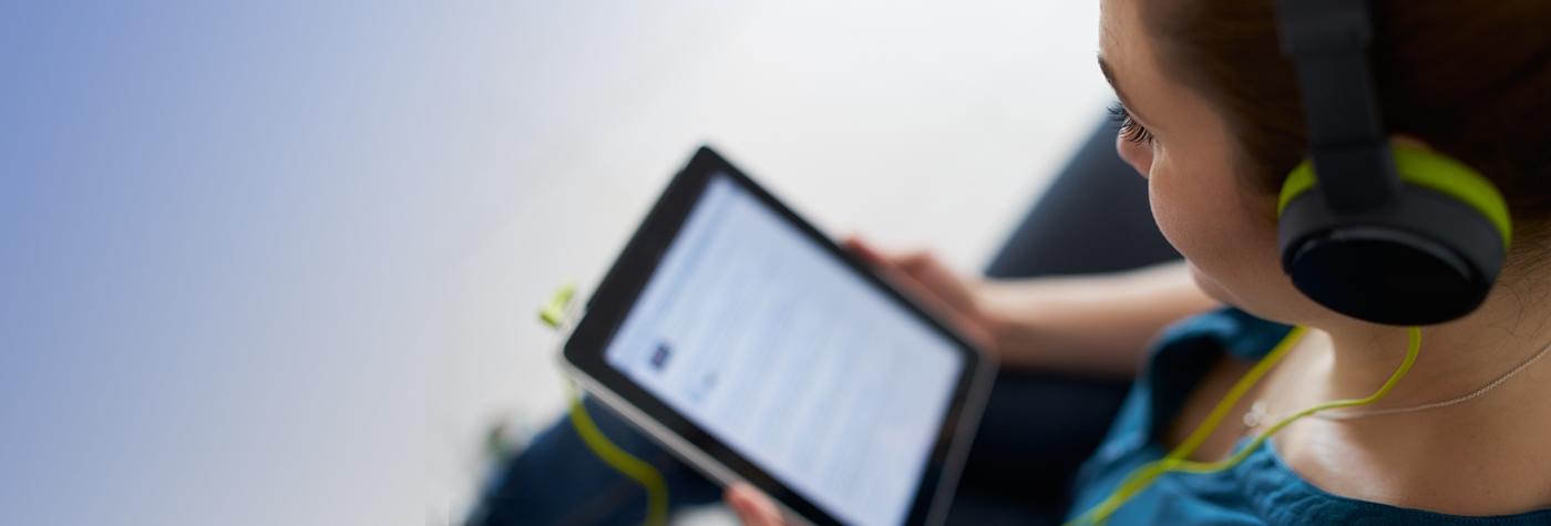 A woman listens to a podcast on her tablet