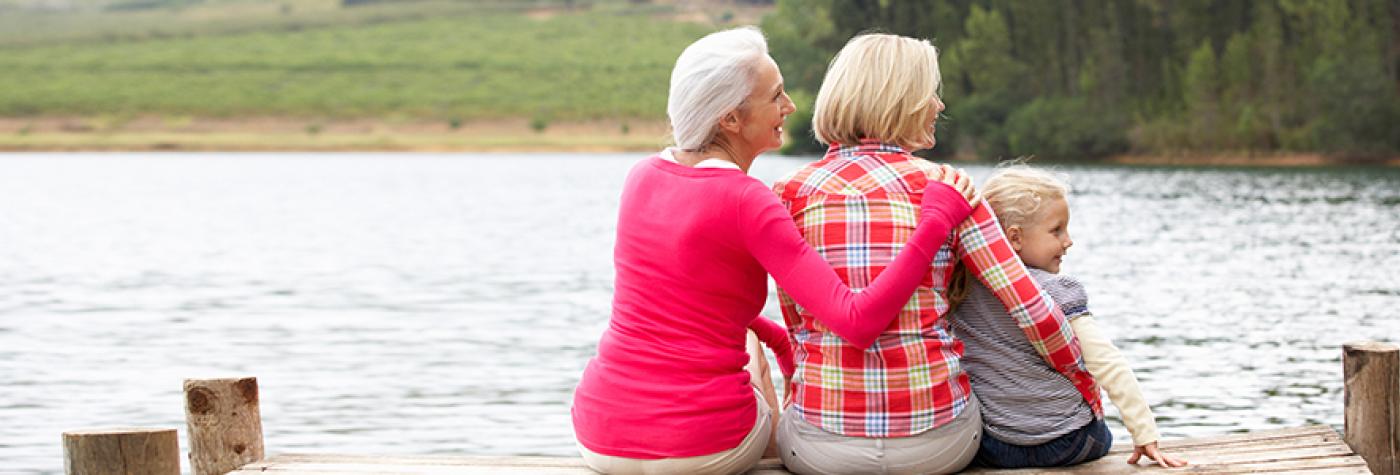 Grandmother, child and grandchild sitting on a dock