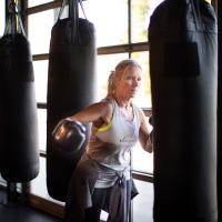 Lindi wears her boxing gloves and works out punching a punching bag.